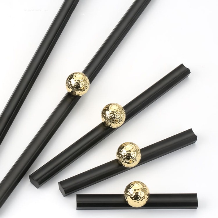 Möbelgriff Nigua – schwarzer länglicher Griff mit dekorativer goldener Kugel für Schränke und Schubladen, moderner Aufsatzgriff, erhältlich im Shop egriffe.at