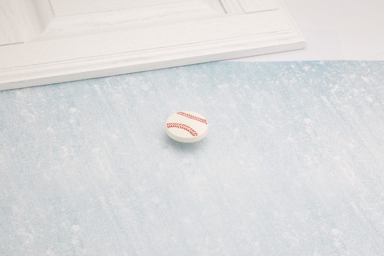 Dziecięca gałka meblowa Baseball w kształcie piłki baseballowej zaprezentowana na jasnym tle