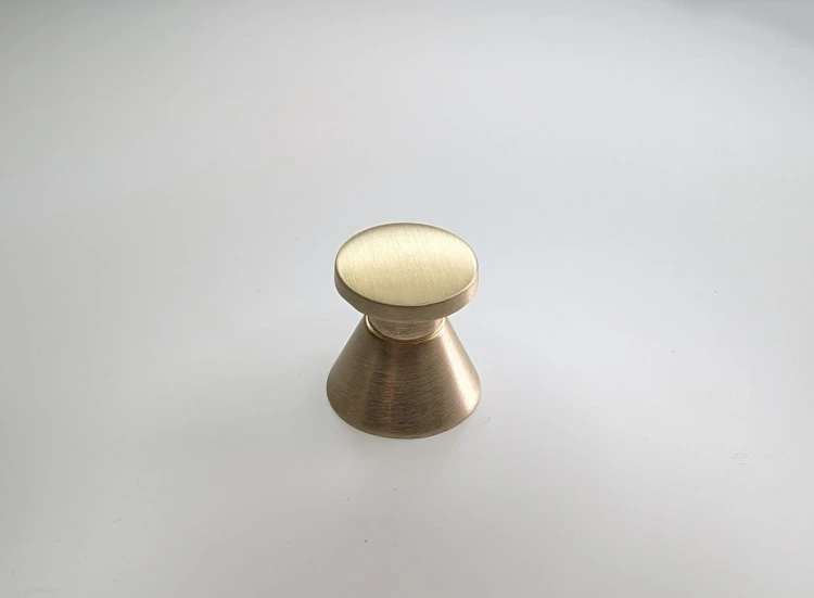 Eleganter goldfarbener Möbelknopf Palomo in moderner Form, präsentiert auf hellem Hintergrund.