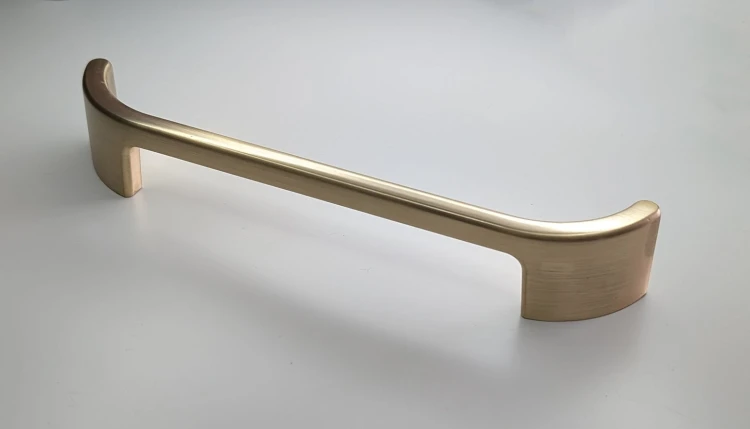 Länglicher goldfarbener Möbelgriff Palomo mit einem Lochabstand von 128 mm.
