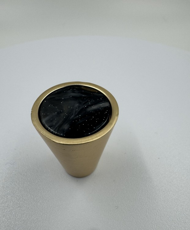 Nahaufnahme in hoher Auflösung des schwarzen Möbelknopfes Luiza mit goldfarbenem Ring.