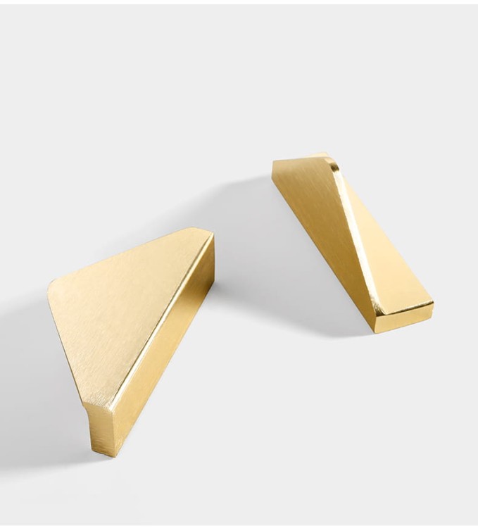Möbelgriff Isa – asymmetrischer Dreiecksgriff mit markanter geometrischer Form. In gebürstetem Gold oder Schwarz, ideal für Küchenfronten, Kommoden, Vitrinen und Schränke in modernen und glamourösen Interieurs.