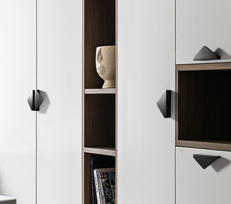 Möbelgriff Isa – asymmetrischer Dreiecksgriff mit markanter geometrischer Form. In gebürstetem Gold oder Schwarz, ideal für Küchenfronten, Kommoden, Vitrinen und Schränke in modernen und glamourösen Interieurs.