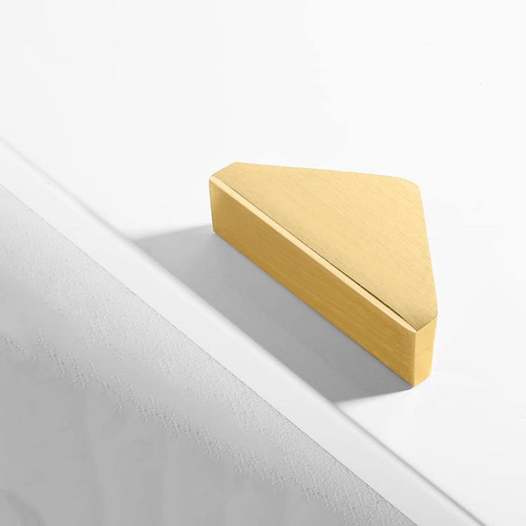 Möbelgriff Isa – asymmetrischer Dreiecksgriff mit markanter geometrischer Form. In gebürstetem Gold oder Schwarz, ideal für Küchenfronten, Kommoden, Vitrinen und Schränke in modernen und glamourösen Interieurs.